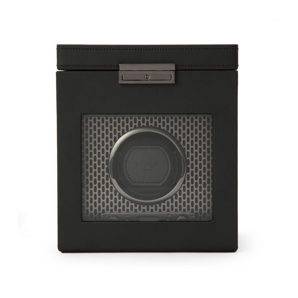 The WOLF 1834 Axis Single Watch Winder With Storage by WOLF is a black, square device with a clear front panel. It showcases a circular mount that holds the watch against a stylish honeycomb-patterned interior. Designed for optimal display, it offers rotation options and includes a metallic latch on top to elegantly secure the lid.