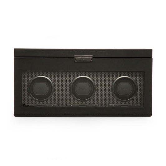 The WOLF 1834 Axis Triple Watch Winder With Storage, designed by WOLF, is a modern black rectangular box made from vegan leather. It features a transparent front panel that reveals four round compartments, each containing items with dark rims and matching centers. This sleek design offers watch winder rotation options for optimal functionality.