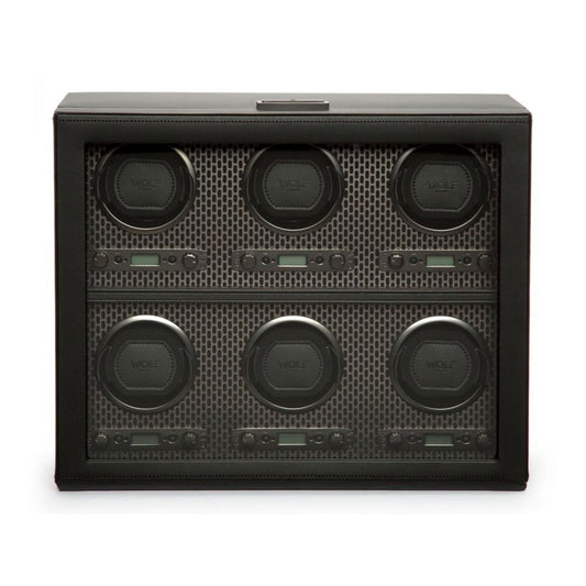 The WOLF 1834 Axis Watch Winder, by the renowned brand WOLF, is a black watch winder featuring a transparent front panel that reveals six compartments. Each compartment includes a round slot adorned with the "WOLF" logo. Its interior features patented technology and a geometric pattern in gray tones, reflecting modern luxury design.