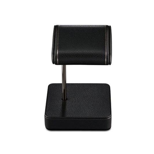 The WOLF 1834 British Racing Single Static Watch Stand by WOLF is an elegant black display piece with a textured vegan leather surface. It features a cylindrical rest supported by a vertical rod attached to a square base, making it perfect for showcasing your favorite watch or bracelet with sophistication.
