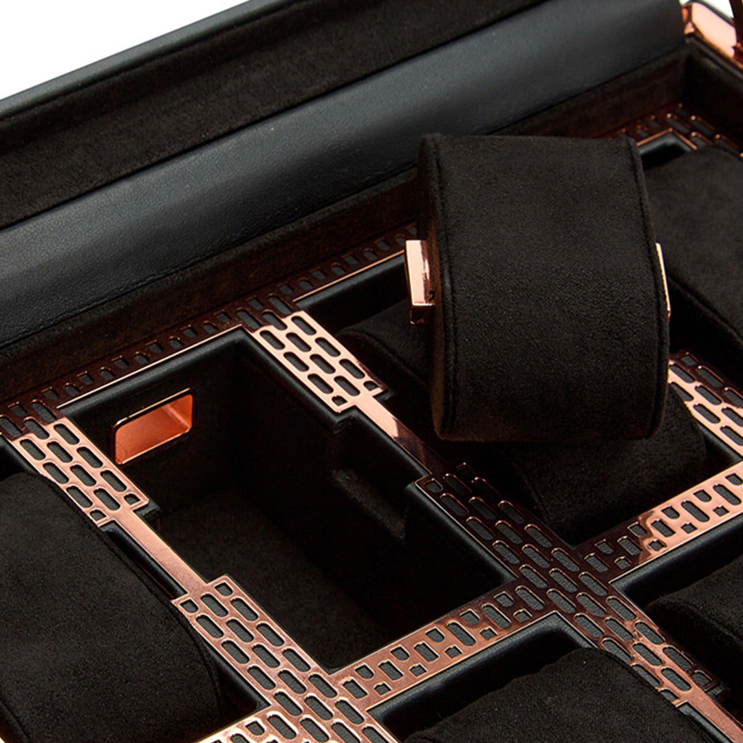 A close-up of the sophisticated WOLF 1834 Axis 10 Piece Watch Box, featuring a refined black and rose gold design with a soft padded interior. One elevated section showcases suspended watch cushions, accentuating its luxurious texture. The box includes a grid of compartments for securely storing multiple watches.