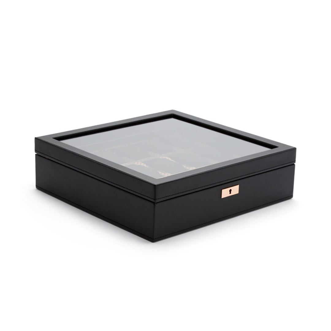 The WOLF 1834 Axis 15 Piece Watch Box by WOLF is a stylish black leather storage solution featuring a glass top and a small keyhole on the front, providing lock and key security. It offers storage for multiple watches, visible through the glass. The surface is smooth with neatly finished edges.