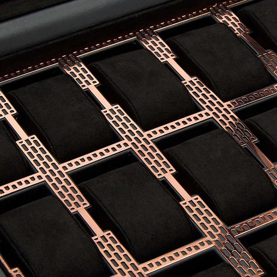 Close-up of the WOLF 1834 Axis 15 Piece Watch Box, showcasing its luxury design with black padded compartments separated by intricate metallic rose gold dividers with a perforated pattern. The contrast enhances the sophisticated design and lock-and-key security of this storage organizer.