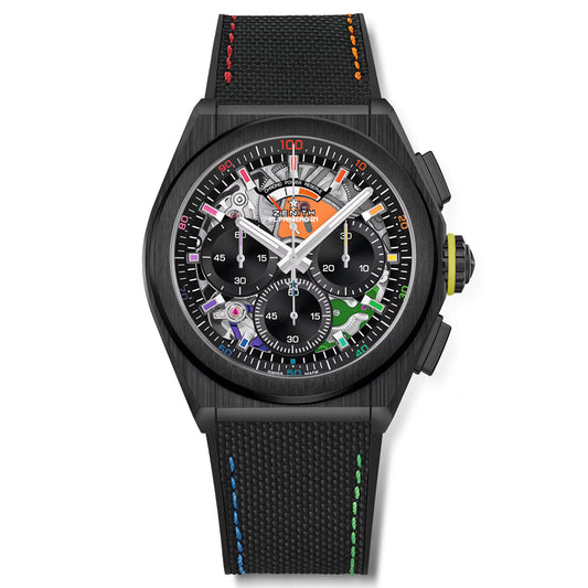 The Zenith Defy El Primero 21 44mm Watch features a black ceramic case and a colorful, intricate dial with visible gears, orange, green, blue, and pink accents. It has multiple subdials, a prominent crown, and rainbow stitching on the textured strap.