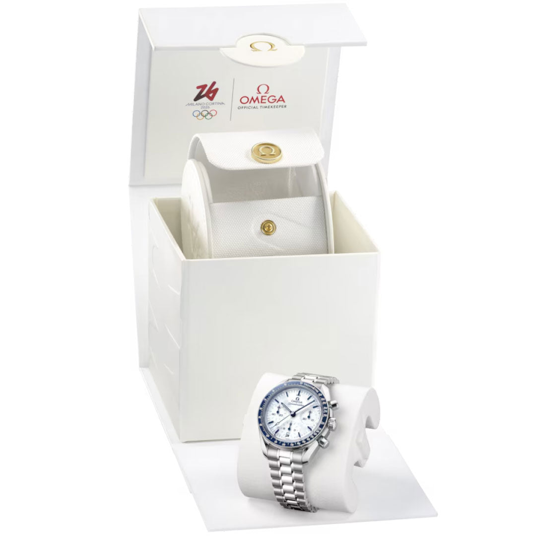 The OMEGA Speedmaster 38 Co-Axial Chronometer Chronograph 38mm Watch Milano Cortina 2026 Edition, a luxury stainless steel timepiece with a silver band, is shown on a cushion before an open white OMEGA box with the brand and Milano Cortina 2026 logos.