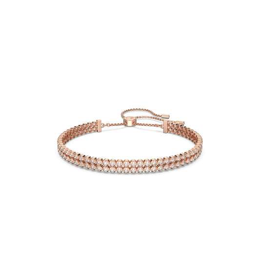 The Swarovski Rose Gold Subtle Bracelet, crafted by Swarovski, showcases two rows of sparkling clear stones set against rose gold plating. This elegant and sophisticated piece features an adjustable sliding clasp for a tailored fit, beautifully enhancing the shimmer of the stones against the metal.