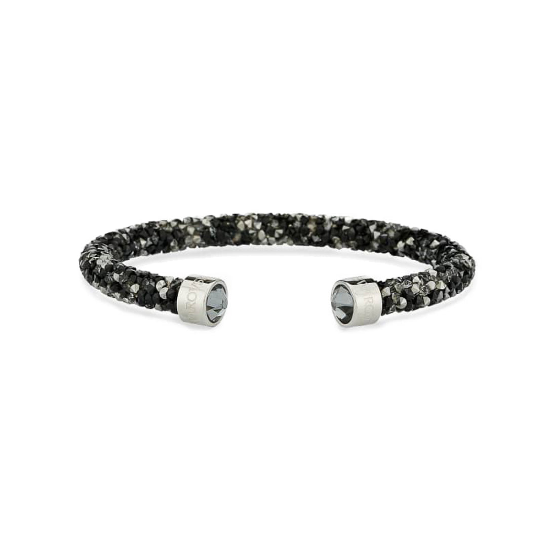 The Swarovski Crystal Dust Cuff, by renowned brand Swarovski, showcases a dazzling black and silver design adorned with brilliant crystals. Its flexible textured band and metallic end caps exude luxury against the pristine white background.