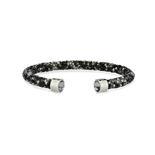 The Swarovski Crystal Dust Cuff, by renowned brand Swarovski, showcases a dazzling black and silver design adorned with brilliant crystals. Its flexible textured band and metallic end caps exude luxury against the pristine white background.