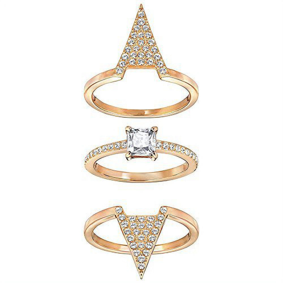 The Swarovski Delta Three Rings Set by Swarovski presents an exquisite combination of three stacked gold rings. The top ring is highlighted by an upward-pointing triangle with embedded gemstones, the middle ring features a square-cut stone set on a rhodium-plated band, and the bottom ring is adorned with clear crystals arranged in a downward-pointing triangle.