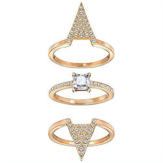 The Swarovski Delta Three Rings Set by Swarovski presents an exquisite combination of three stacked gold rings. The top ring is highlighted by an upward-pointing triangle with embedded gemstones, the middle ring features a square-cut stone set on a rhodium-plated band, and the bottom ring is adorned with clear crystals arranged in a downward-pointing triangle.