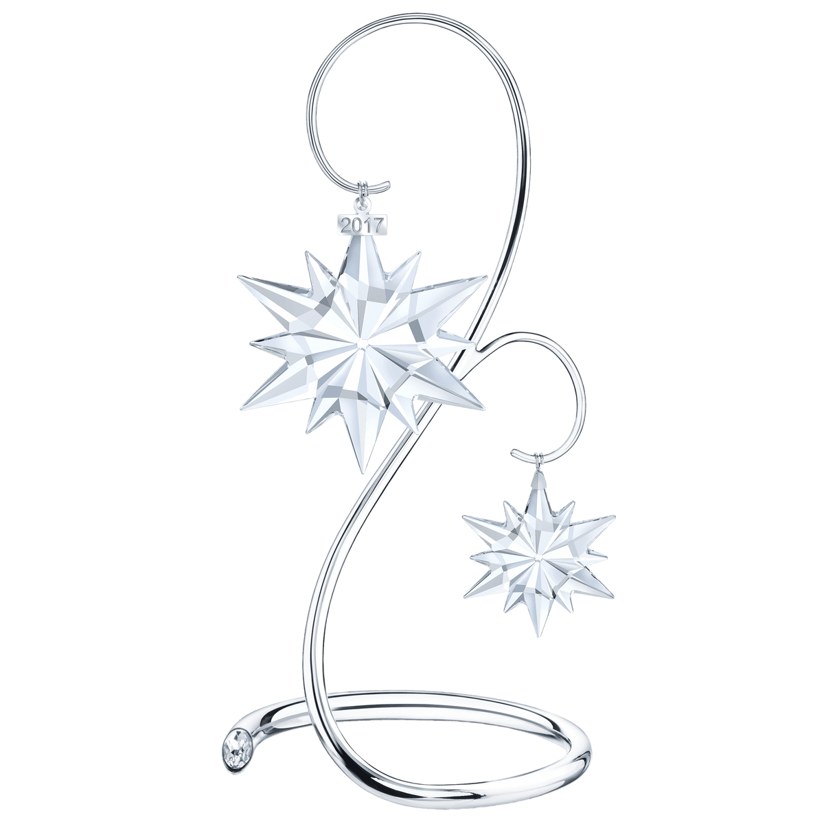 Two clear crystal star ornaments from the Swarovski Annual Edition Ornament 2017 collection by Swarovski are elegantly suspended from a sleek silver curved metal stand, offered at Raffi Jewellers. The larger star features an etched “2017,” beautifully showcased against a plain white background that accentuates the refined style associated with Swarovski Canada.