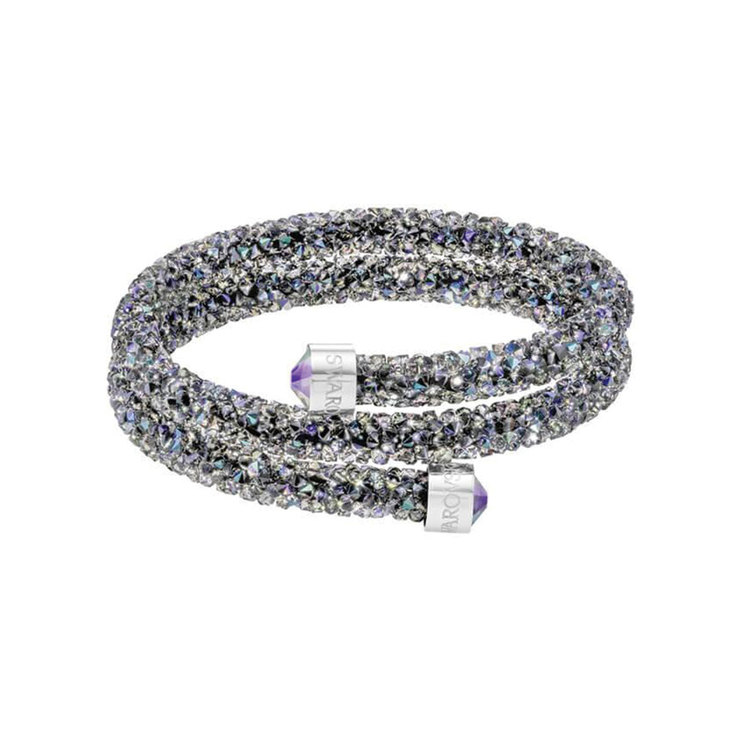 Introducing the Swarovski Crystal Dust Cuff, a dazzling and adaptable bracelet adorned with glimmering black and purple crystals. This piece is enhanced by two cylindrical end caps engraved with text, exuding a sense of luxury and elegance.