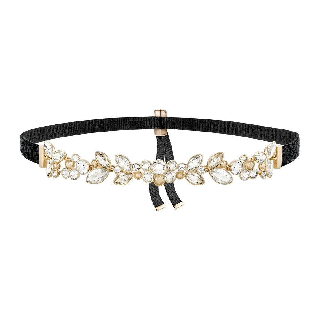 A decorative belt featuring a black elastic band adorned with gold floral embellishments and sparkling gemstones, similar to those found in a fine jewelry collection. Beneath the ornate design, a small black bow adds an elegant touch akin to the Swarovski Garance Choker by Swarovski.