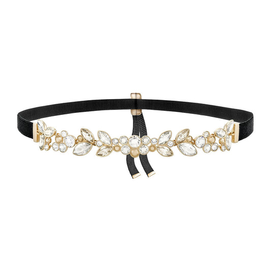 A decorative belt featuring a black elastic band adorned with gold floral embellishments and sparkling gemstones, similar to those found in a fine jewelry collection. Beneath the ornate design, a small black bow adds an elegant touch akin to the Swarovski Garance Choker by Swarovski.