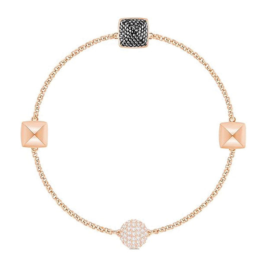 A finely crafted piece from the Swarovski Remix Collection Bracelet, this exquisite gold bracelet by Swarovski features three geometric charms: a circular charm encrusted with small white stones, a square charm adorned with black crystals, and a plain gold pyramid shape. It is elegantly designed with a thin, simple chain and rose gold plating.