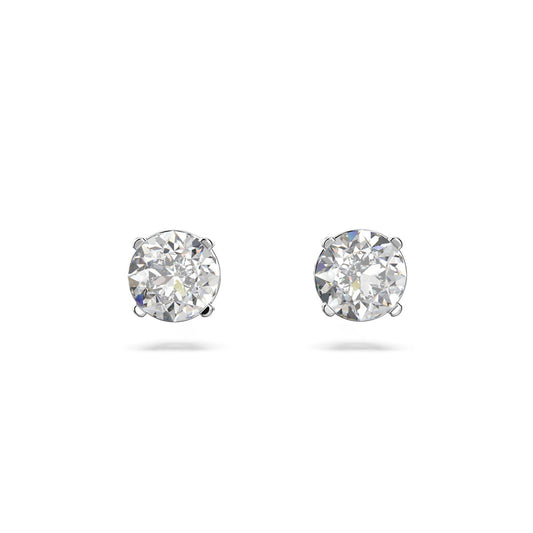 The Swarovski Attract Round Pierced Earrings feature sparkling diamonds with rhodium plating set in a simple silver prong design, creating an elegant piece of jewelry, displayed on a plain white background.