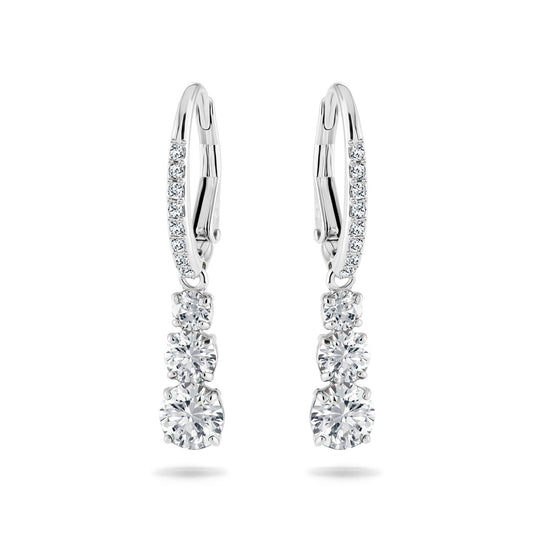 The Swarovski Attract Trilogy Earrings, crafted by Swarovski, elegantly display three round, shimmering diamonds arranged in a refined linear design. Encased in a sleek silver setting with rhodium plating, the earrings are further accentuated by additional small diamonds on the hooks for an added touch of sophistication.