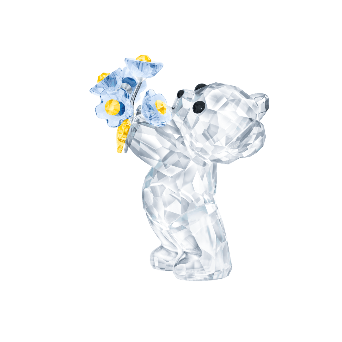 The Swarovski Kris Bear - Forget-me-not by Swarovski is a crystal figurine that stands upright, holding a sparkling bouquet of blue and yellow forget-me-not flowers, set against a plain white background.