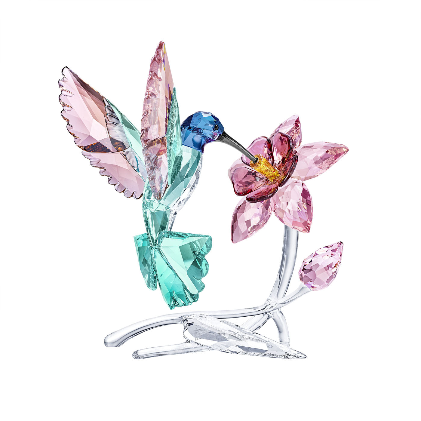 The Swarovski Humming Bird Crystal Home Decor piece artfully showcases a delicate hummingbird in mid-flight, crafted in enchanting blue, pink, and green tones. It is seen drinking from a pink crystal flower featuring a vibrant yellow center. This exquisite item by Swarovski rests gracefully on a transparent base, making it an ideal addition to any nature lover's collection.