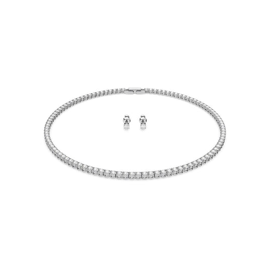 The Swarovski Round Cut Tennis Deluxe Necklace and Earrings Set presents an aura of elegance and sophistication. The necklace, plated in rhodium, showcases a continuous line of sparkling Swarovski crystals, while the accompanying earrings are classic round diamond studs, all beautifully set against a white background.