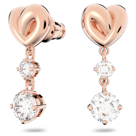 The Swarovski Lifelong Heart Drop Earrings feature a rose gold heart design adorned with dangling round diamonds. Each earring elegantly displays a small diamond beneath the heart, culminating in a larger diamond at the bottom, all set in a pronged setting for an exquisite sparkle.