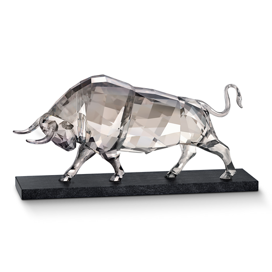 The Swarovski Soulmates Bull Crystal Home Décor piece features a transparent, geometric design with sleek, angular shapes standing on a black rectangular base. Its reflective surfaces enhance an elegant and modern aesthetic against the plain black backdrop, showcasing the exquisite craftsmanship that Swarovski is renowned for.