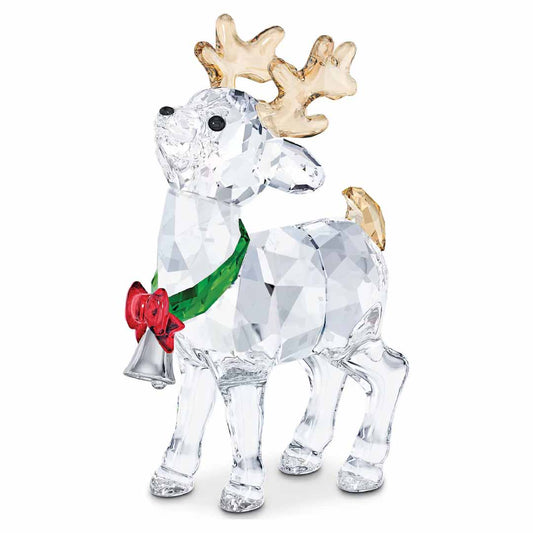 The Swarovski Santa's Reindeer Home Décor features elegant crystal antlers, a vivid red bow, and a silver bell adorning its neck. Its gold antlers and tail elegantly enhance the faceted design, reflecting light beautifully. This festive decoration radiates brilliantly against a simple background.