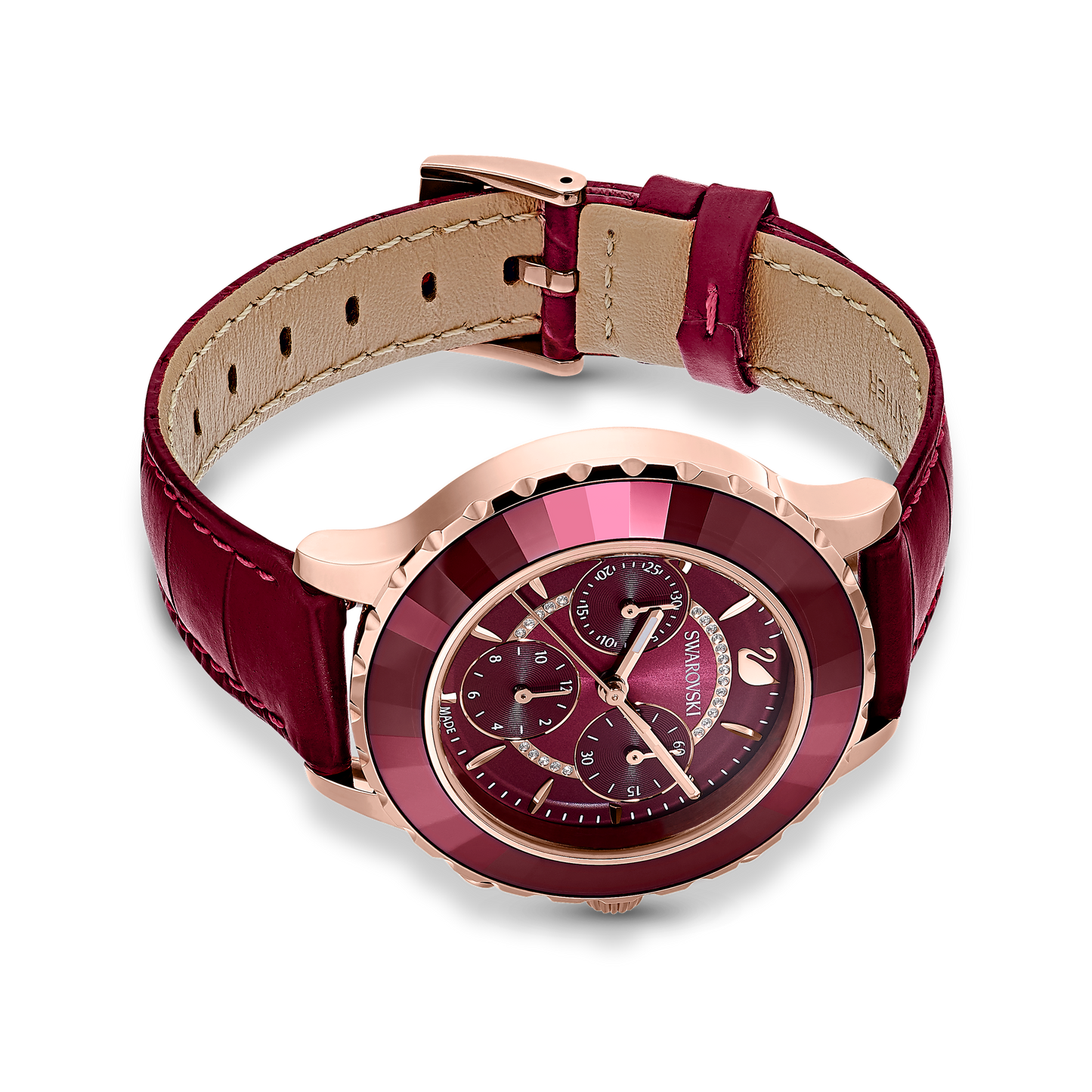 This Swiss-made Octea Lux Chrono watch from Swarovski features a burgundy leather strap and rose gold-tone case. It includes a dark red dial with multiple small chrono dials accented by gleaming gold markings and hands, all adorned with Swarovski elements that elegantly stand out against a sleek black background.