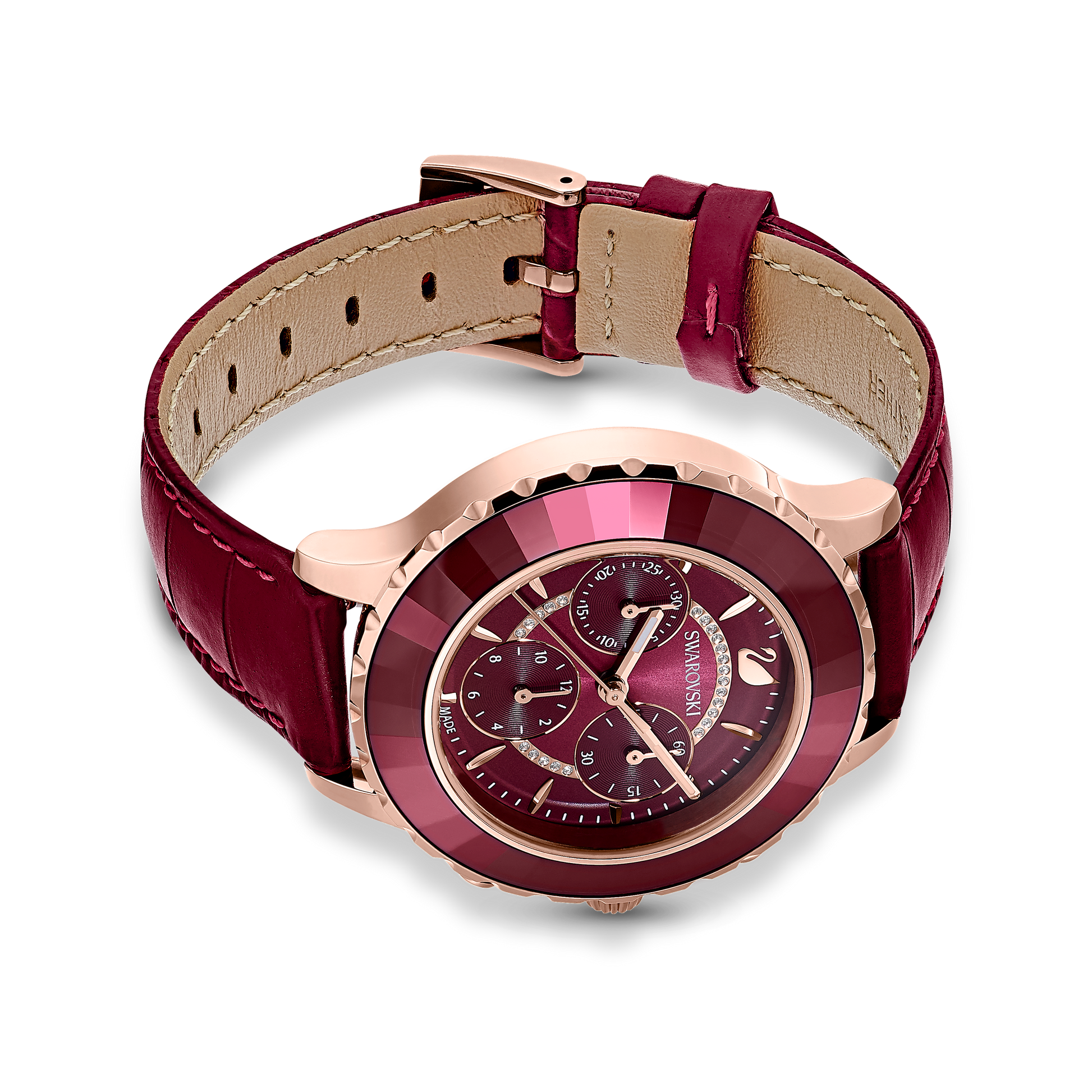 This Swiss-made Octea Lux Chrono watch from Swarovski features a burgundy leather strap and rose gold-tone case. It includes a dark red dial with multiple small chrono dials accented by gleaming gold markings and hands, all adorned with Swarovski elements that elegantly stand out against a sleek black background.