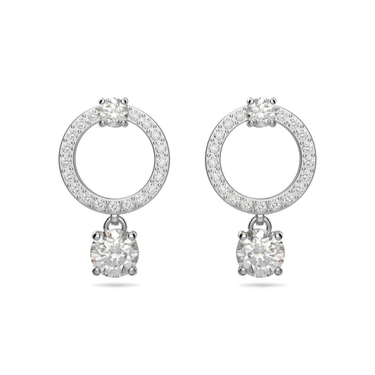 The Swarovski Attract Hoop Earrings showcase elegant silver loops adorned with sparkling pavé gems, each holding a larger round, diamond-like stone. The symmetrical design shines brightly against a plain white background, exuding timeless beauty and sophistication.