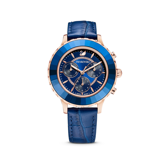 The Octea Lux Chrono watch by Swarovski, Swiss Made with a rose gold-tone finish, features a sophisticated round face with multiple dials and a polished stainless steel case. Its textured blue leather strap complements the watch's elegant design, making it an ideal choice for those who value the precision of Quartz movements.