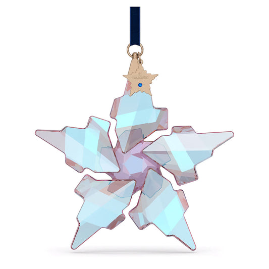 Introducing the Swarovski 2021 Annual Edition 30th Anniversary Ornament—a captivating multi-faceted crystal snowflake decoration adorned with a blue ribbon for hanging. This exquisite piece by Swarovski features an intricate star shape and includes a small gold tag at the top. The collectible ornament beautifully reflects shades of pink and blue, truly embodying the essence of a crystal star.