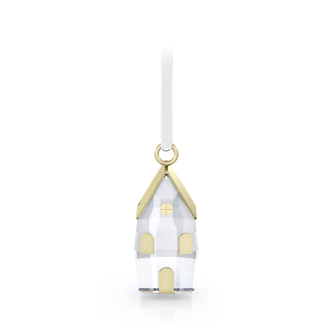 The Swarovski Holiday Magic Winter Village Ornament Home Décor, crafted by Swarovski, showcases crystal facets and a gold-colored roof, elegantly suspended from a white ribbon, making it the perfect holiday decoration.