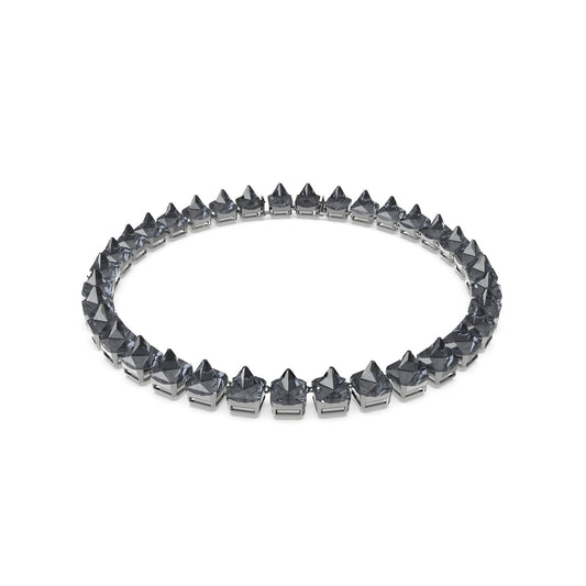 The Swarovski Pyramid Cut Crystal Ortyx Necklace, a round, silver accessory adorned with pyramid-cut crystals forming studs along its entire length, creates a striking spiked appearance. Photographed against a plain white background, it showcases the metallic shine and geometric flair of this edgy design.