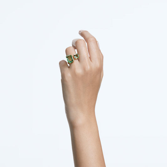 Against a plain white background, a hand is raised wearing two Swarovski Millenia Open Rings featuring large green octagon-cut crystals. The fingers are elegantly positioned to highlight the jewelry from the renowned Swarovski Millenia collection.