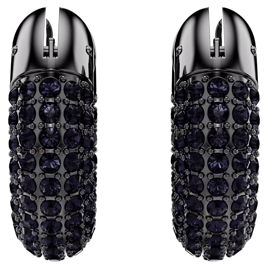 Two refined, bullet-shaped objects from Swarovski, the Dextera Hoop Earrings, stand upright on a reflective white surface, adorned with dark gemstones and elegant ruthenium plating. The design boasts a textured and luxurious appearance with intricate detailing of small, shiny stones.