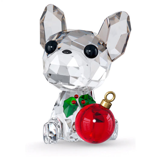 The Swarovski Holiday Cheers French Bulldog Home Décor piece beautifully embodies the holiday spirit, featuring large black eyes. This charming figurine is adorned with green holly and red berries around its neck and holds a shiny red Christmas ornament, with its faceted design reflecting light magnificently.