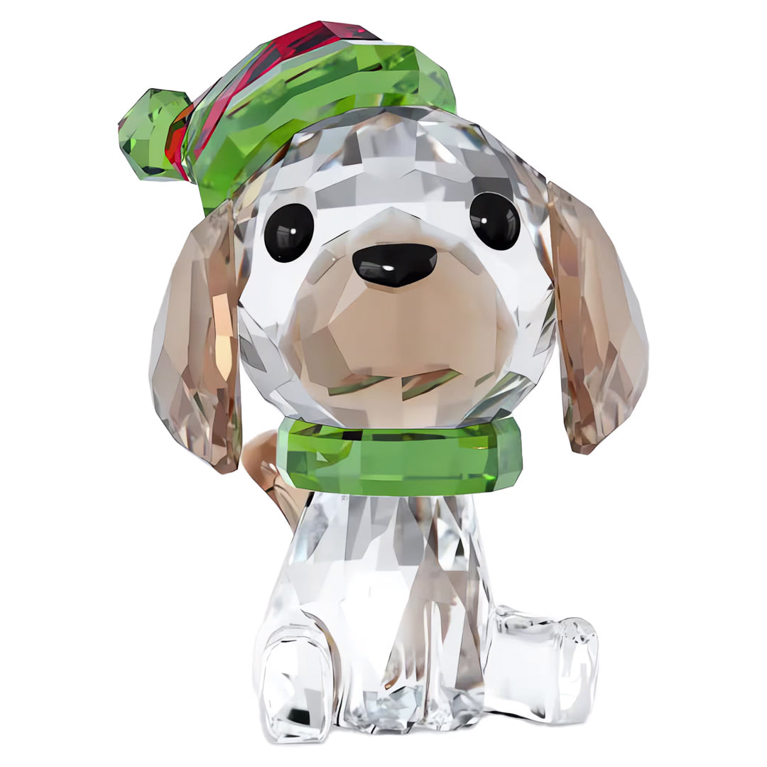 The Swarovski Holiday Cheers Beagle Home Décor piece from Swarovski is a petite, crystal figurine of a beagle adorned with a festive green and red hat and collar. Its floppy ears and intricately-cut facets make it a dazzling addition to any holiday display against a plain white background.