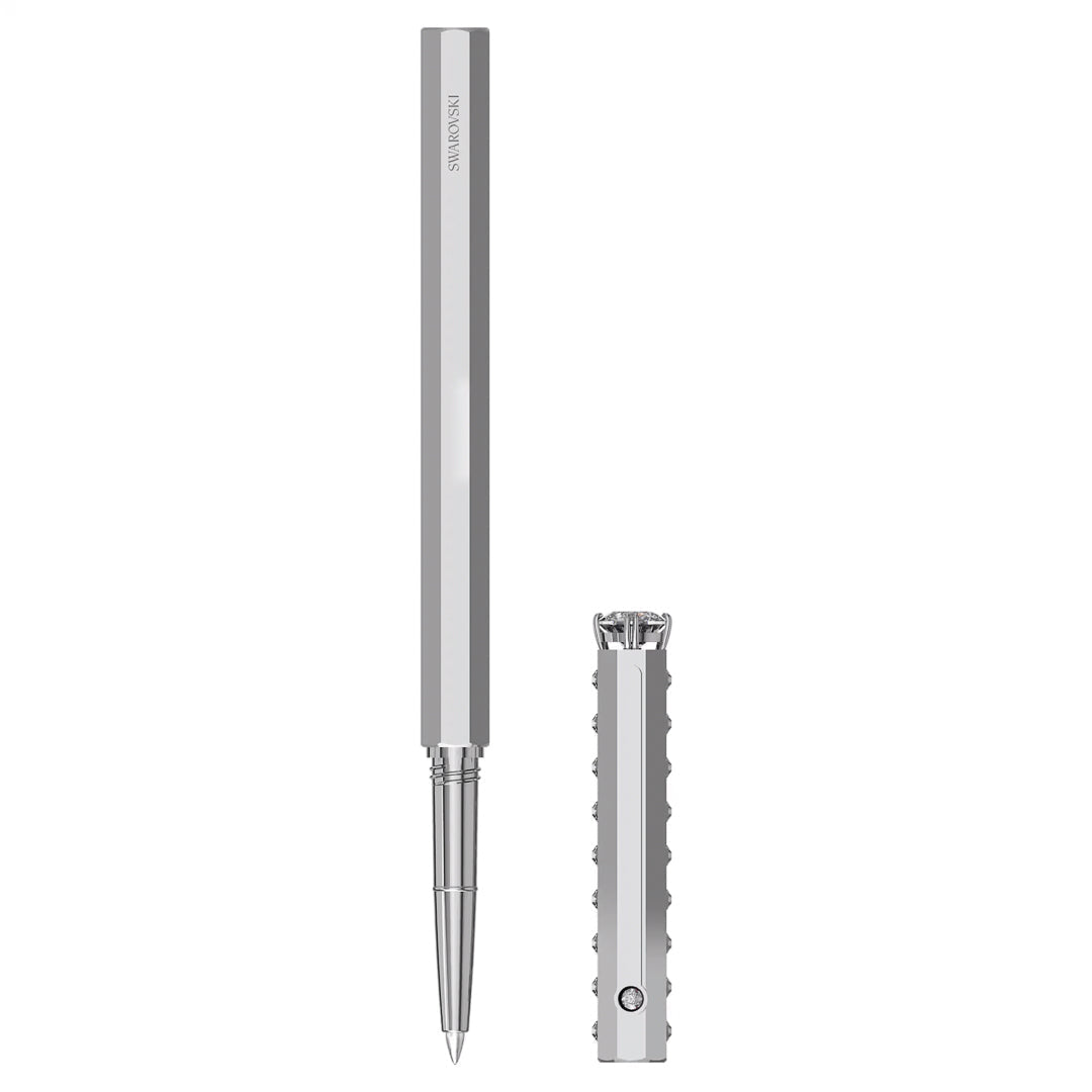 The image showcases the Swarovski Ballpoint Pen, characterized by its sleek metallic finish and angular barrel design. The pen is displayed with its cap removed and set aside, exposing the pen tip. The cap's textured pattern along its length adds a touch of chrome-plated elegance.