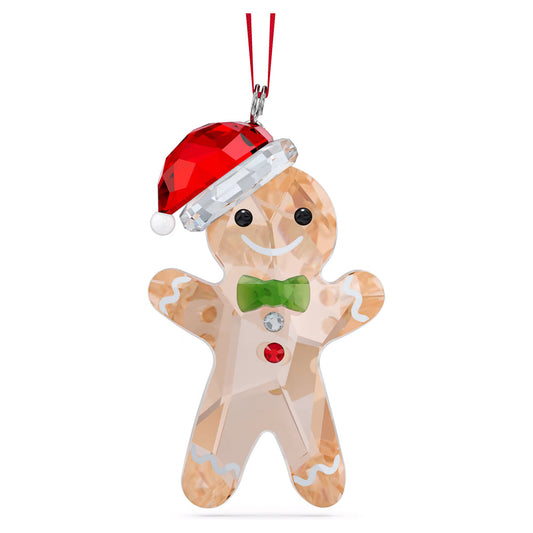 The Swarovski Holiday Cheers Gingerbread Man Ornament Home Décor piece dazzles with crystal embellishments. It features a cheerful design with a bright red Santa hat, a green bow tie, and endearing red buttons. Its smiling black eyes and intricate icing details on the arms and legs contribute to its delightful charm as it hangs from a vibrant red string.