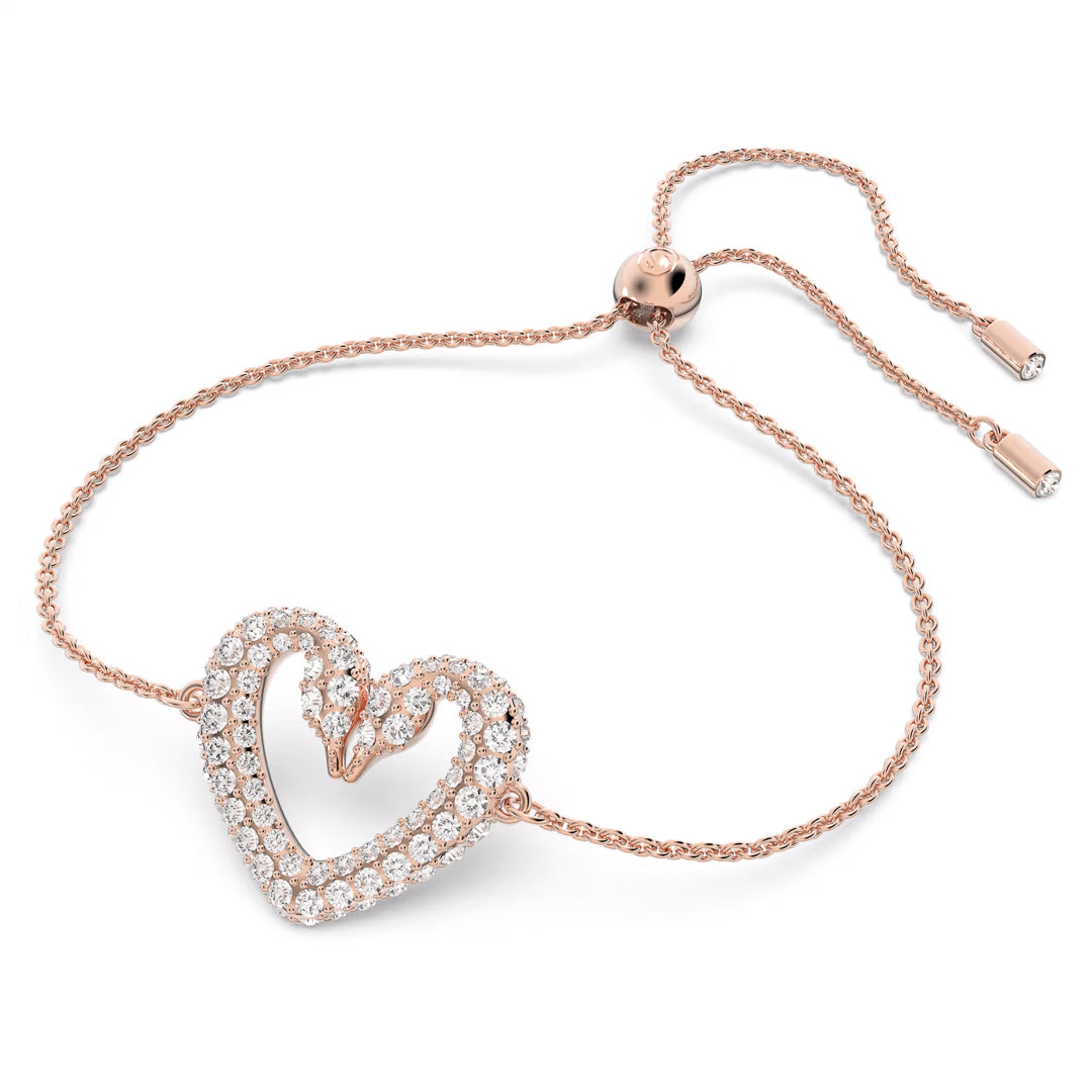 The Swarovski Sublima Bracelet by Swarovski is a rose gold-tone piece featuring a heart-shaped pendant adorned with sparkling crystal pavé. It includes an adjustable sliding clasp for a personalized fit.