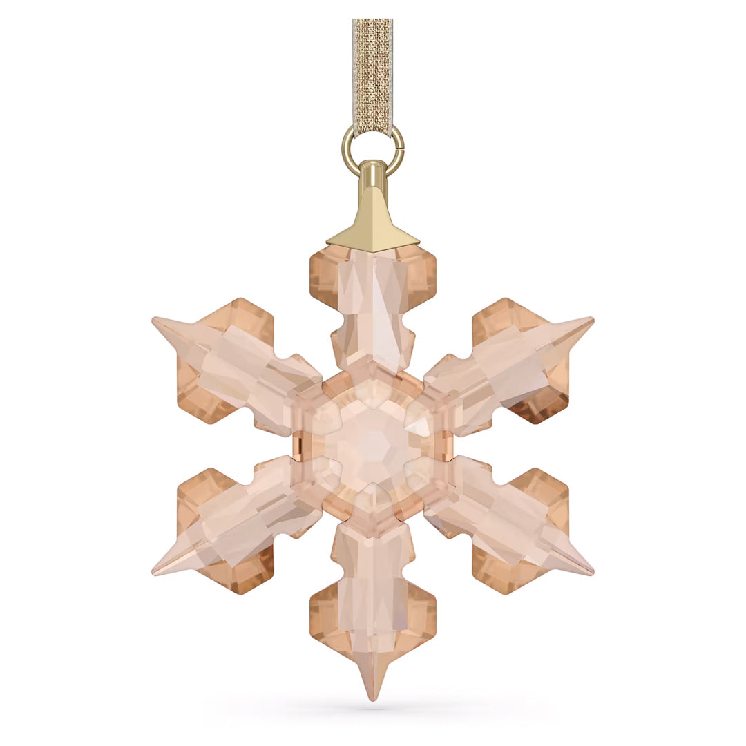 A Swarovski Festive Ornament Home Décor piece, designed by Swarovski, features a crystal snowflake with a gold-toned hue that hangs elegantly from a shimmering gold ribbon. This annual edition for 2022 showcases symmetrical, faceted arms that create an enchanting sparkling effect, perfect for enhancing any holiday décor.