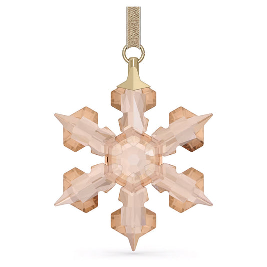A Swarovski Festive Ornament Home Décor piece, designed by Swarovski, features a crystal snowflake with a gold-toned hue that hangs elegantly from a shimmering gold ribbon. This annual edition for 2022 showcases symmetrical, faceted arms that create an enchanting sparkling effect, perfect for enhancing any holiday décor.