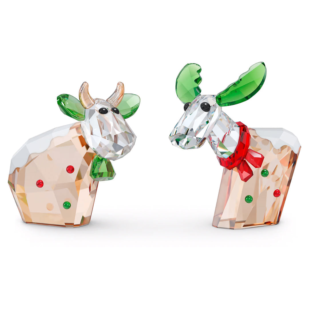 The Swarovski Mo & Ricci Holiday 2022 Annual Edition Home Décor brings together two exquisite collectible characters: a bull showcasing gold horns, green ears, and a snow-dusted back, and a reindeer featuring green antlers, a red nose, and an elegant bow. These festive pieces from Swarovski are beautifully highlighted with red and green accents.