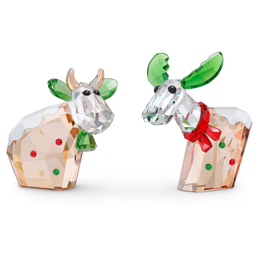 The Swarovski Mo & Ricci Holiday 2022 Annual Edition Home Décor brings together two exquisite collectible characters: a bull showcasing gold horns, green ears, and a snow-dusted back, and a reindeer featuring green antlers, a red nose, and an elegant bow. These festive pieces from Swarovski are beautifully highlighted with red and green accents.