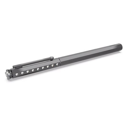 The Swarovski Ballpoint Pen, a product of Swarovski, boasts a sleek metallic appearance with a flat, elongated design and a cap clip. It is elegantly adorned with small crystals embedded along its side and offers a reflective, shiny finish, making it an exquisite addition to the Millenia Family.