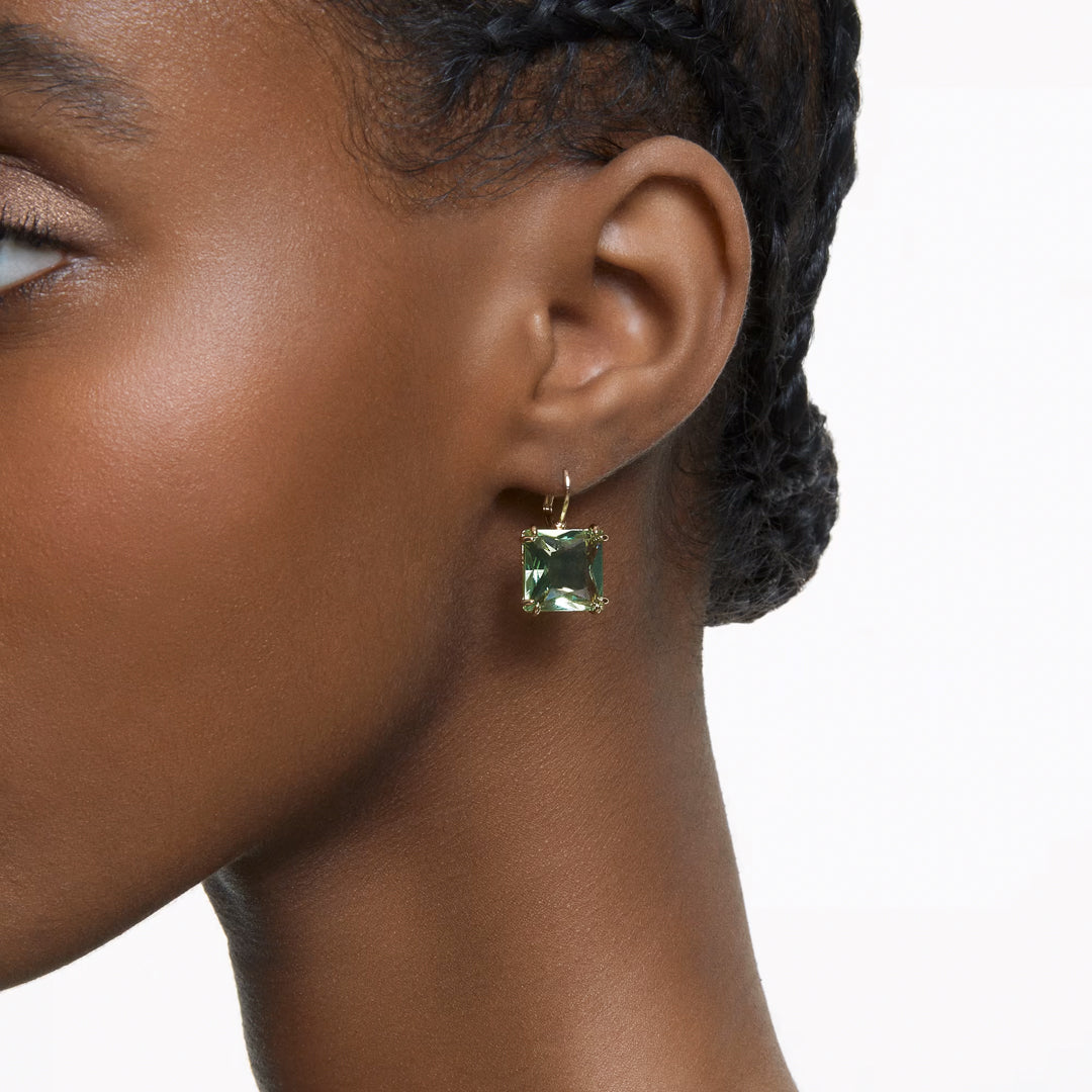 Close-up of a person wearing the Swarovski Millenia Drop Earrings featuring square-cut crystals from Swarovski. The individual's hair is styled in braids, pulled back, against a white background that highlights the earrings' striking design.