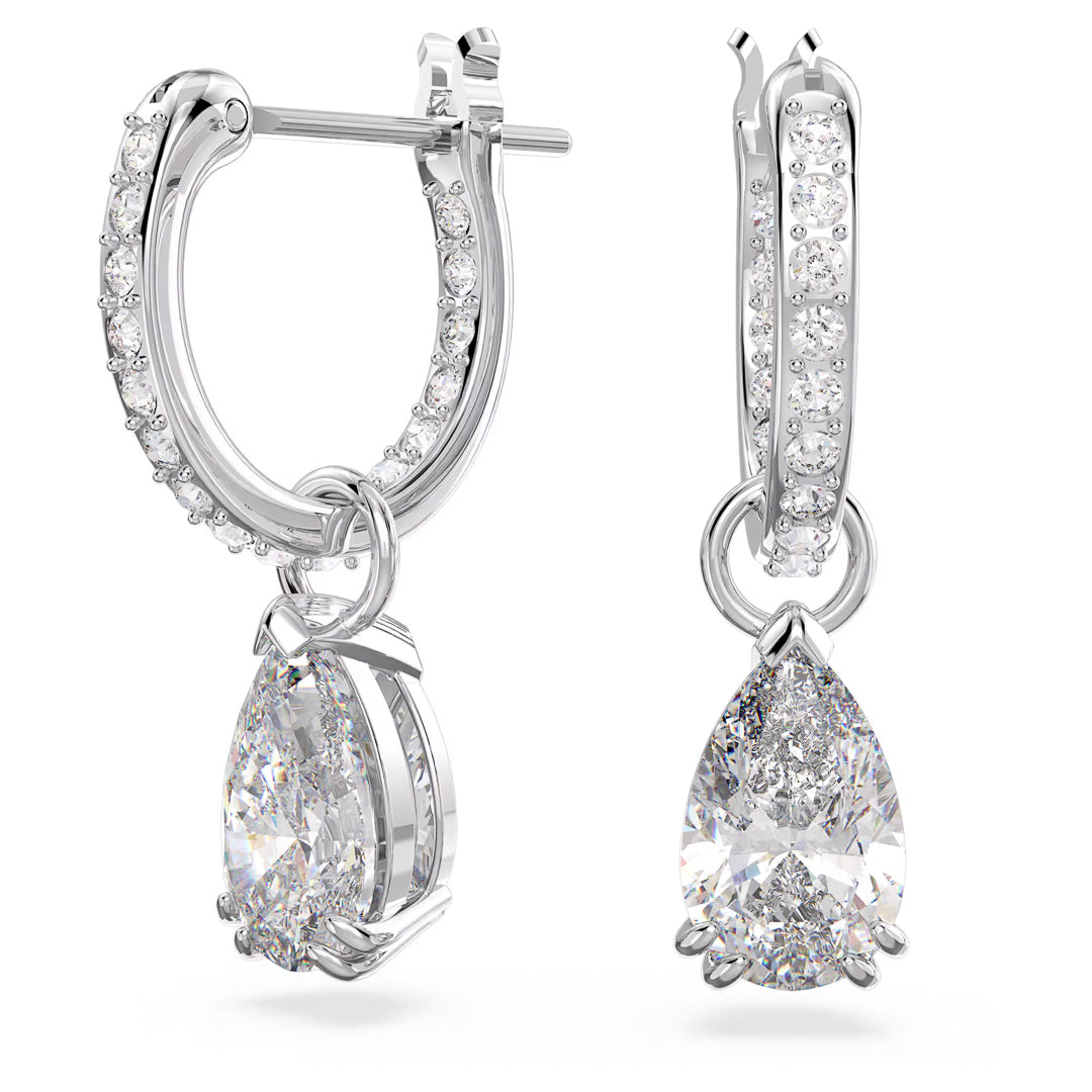A close-up of the Swarovski Stilla Stud Earrings by Swarovski showcases the elegant design featuring small zirconia embellishments and hanging pear-shaped diamond pendants. These earrings are intricately crafted with sparkling details and finished with rhodium plating for a polished look.
