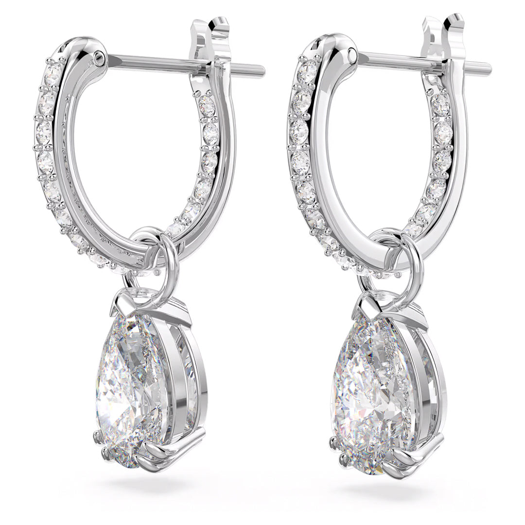 Introducing the Swarovski Stilla Stud Earrings by Swarovski: these elegant silver hoop earrings, rhodium plated to enhance their shine, feature dazzling diamond-like stones. Each earring is adorned with a teardrop-shaped clear gem pendant and smaller Zirconia accents on the hoops for a luxurious and sophisticated design.