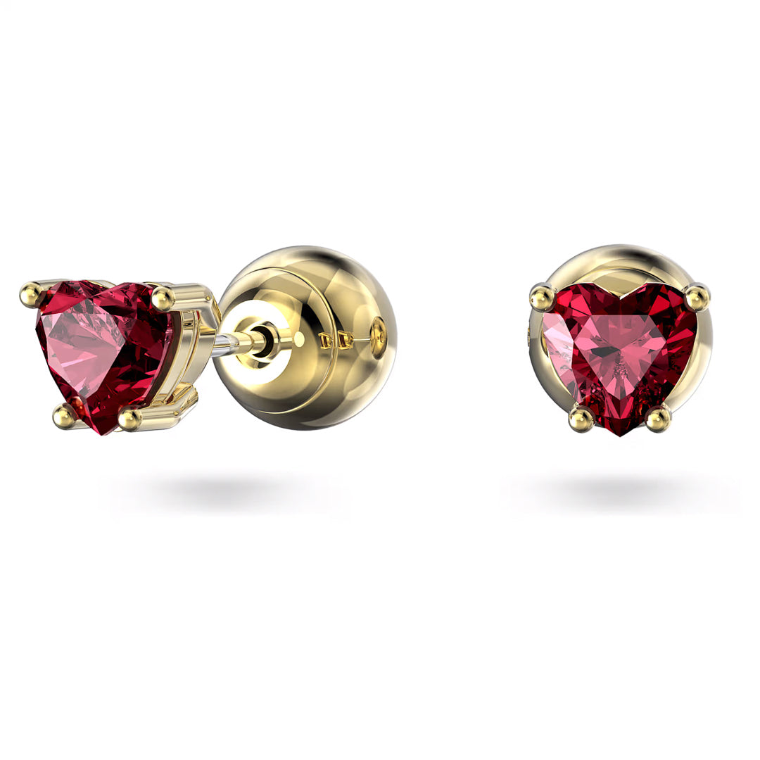 Introducing the Swarovski Chroma Stud Earrings: a pair of gold-tone plated stud earrings featuring heart-shaped red gemstones. These elegant earrings, adorned with zirconia, are beautifully displayed from both a side angle and a front angle against a plain white background. Crafted by the renowned brand Swarovski, they perfectly blend sophistication and charm.